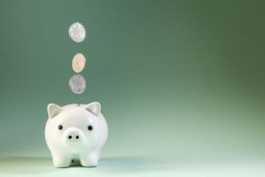 Coins falling into a white piggy bank