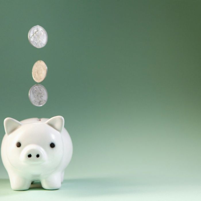 Coins falling into a white piggy bank